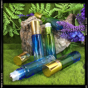blue and green and blue and clear multiple glass vial roller ball perfume bottles displayed on green woodland background with purple flowers 