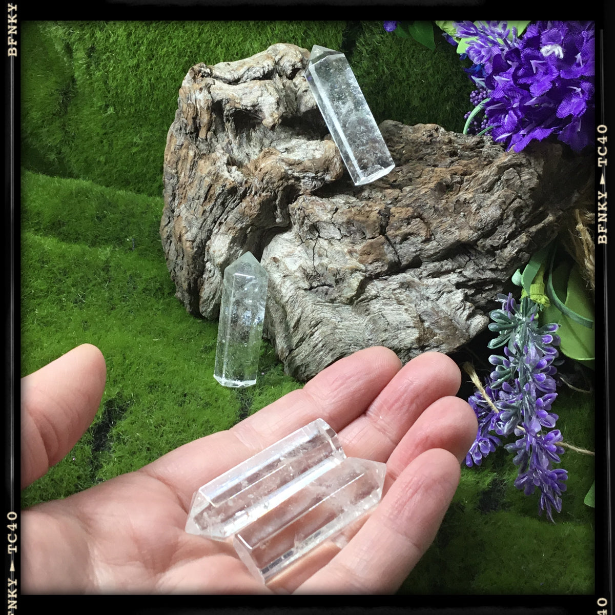 hand showing two  clear quartz mini generators and more in background 